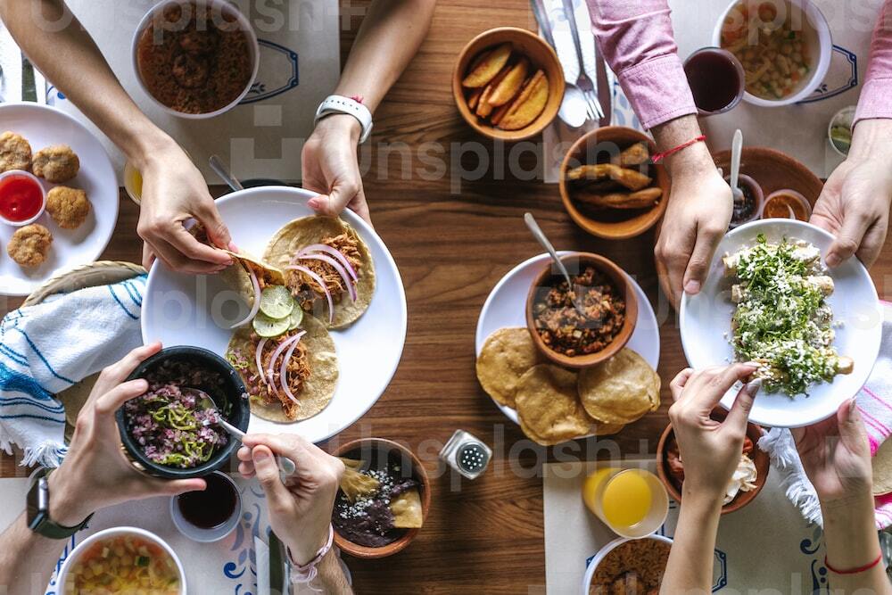 group of latin Friends eating Mexican Tacos and traditional food, snacks and peoples hands over table, top view. Mexican cuisine Latin America