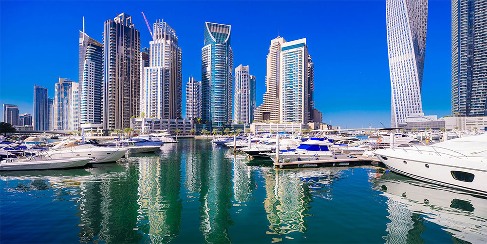 Aerial view of Dubai Marina area with luxury yachts, waterfront promenade and Dubai Tram