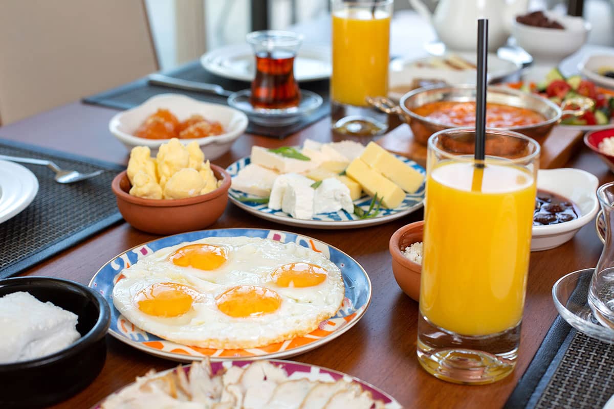 A plate of french toast with fresh juices and poached eggs in the background